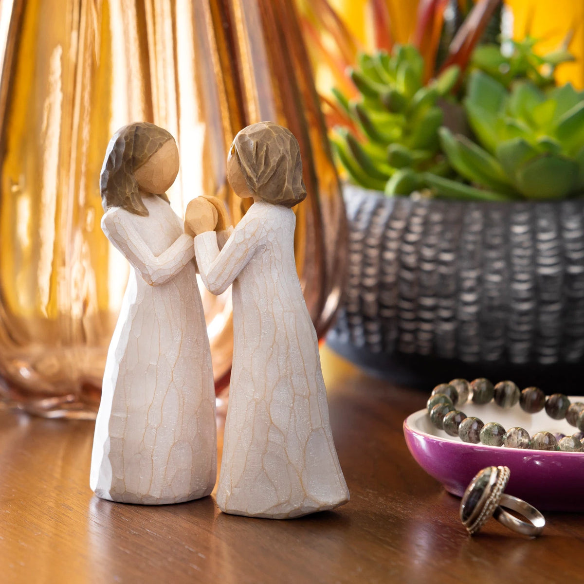 Willow Tree Sisters by Heart, two separate 4.5”h hand-painted standing resin figures in cream dresses with hands that fit together, on dresser with jewelry and succulent