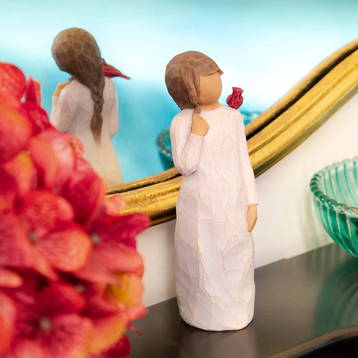 Willow Tree Messenger, 5.5”h hand-painted standing resin figure in cream dress with red cardinal perched on shoulder, on table by mirror