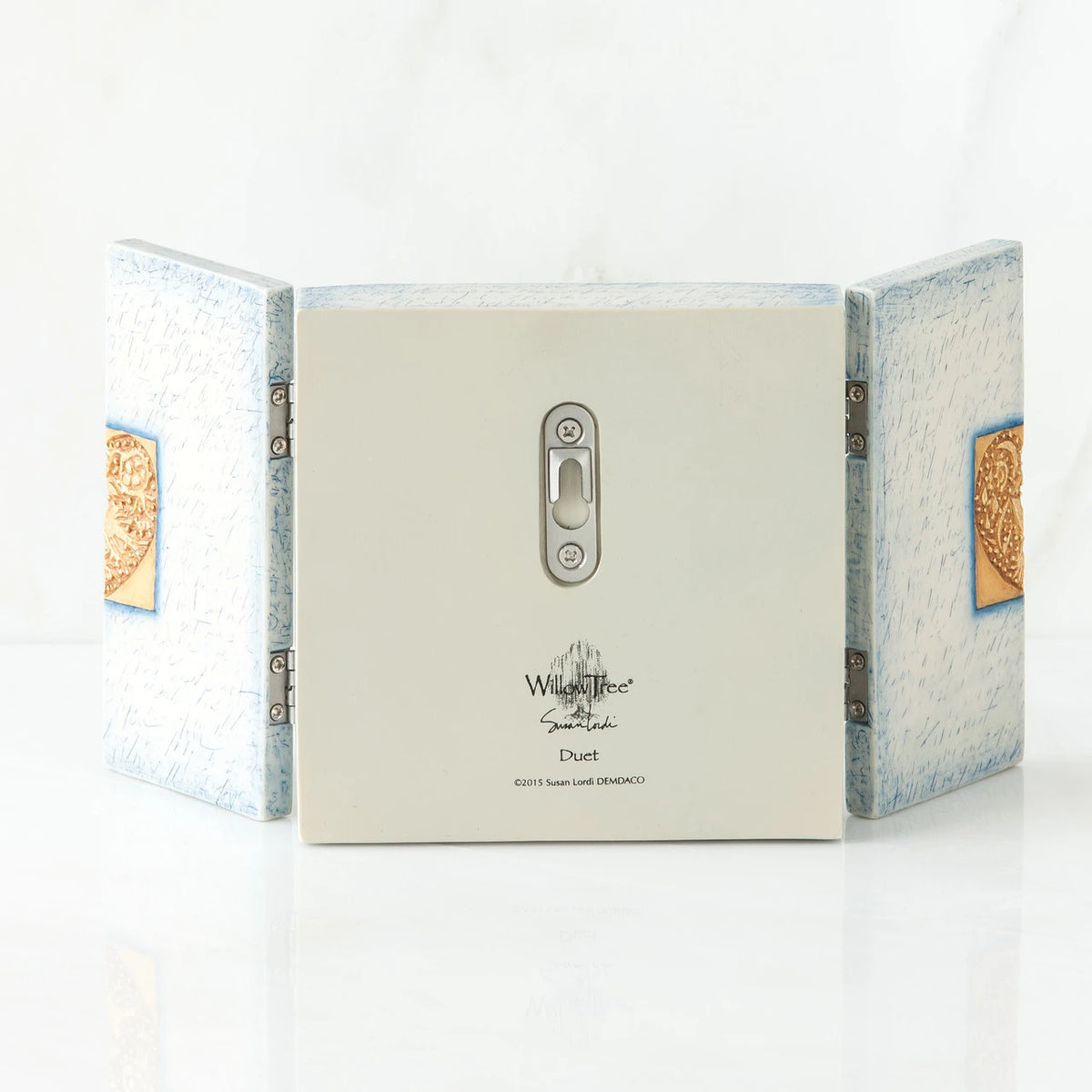 Back side of wooden white/blue book with silver key hole showing and willow tree printed in black