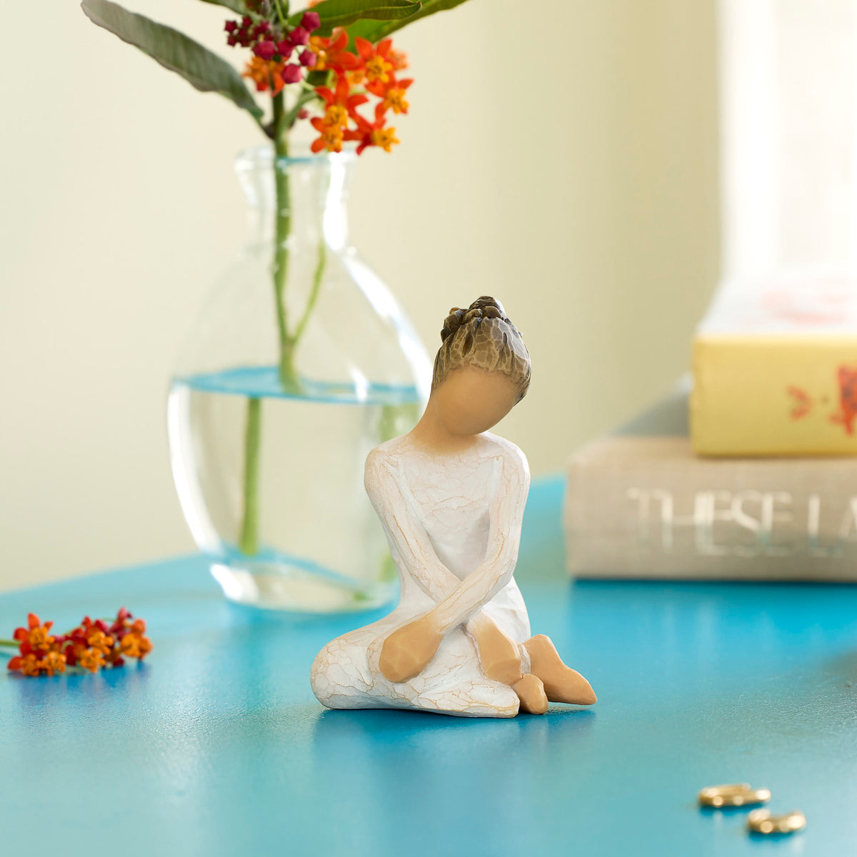 Willow Tree Serenity, 3.5”h hand-painted seated figure in cream dress, arms crossed in balletic pose, on blue table with books