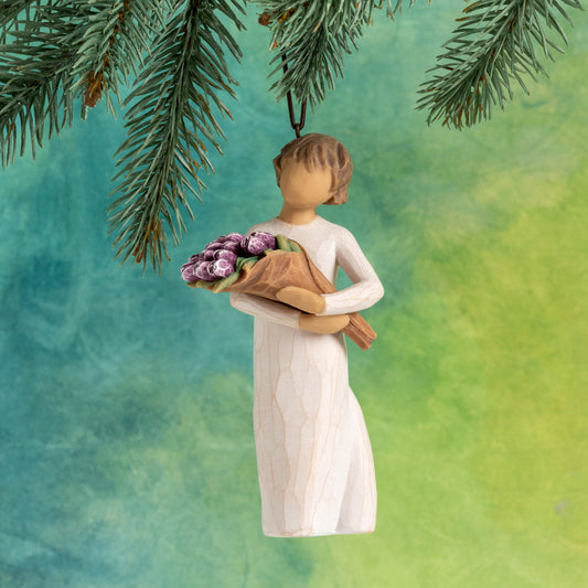 Willow Tree Surprise Ornament 4”h hand-painted resin angel in cream dress, holding large bouquet of purple tulips, brown elastic cord, hanging in front of deep teal painting