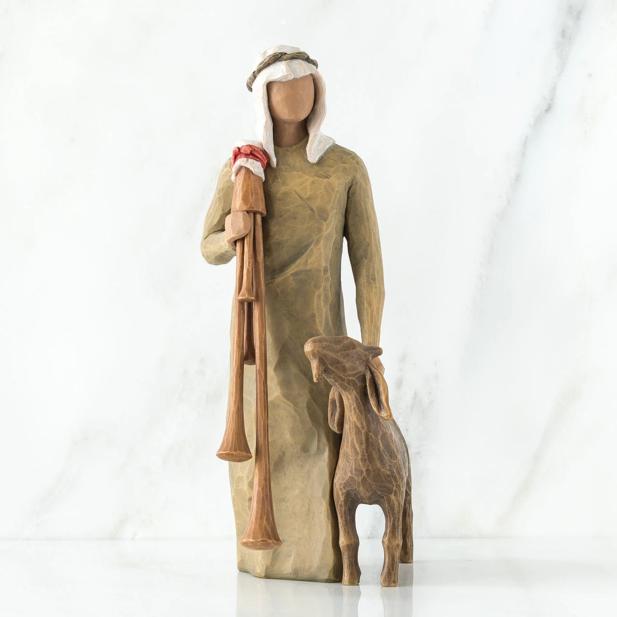 Wise man figurine standing in light brown attire with white headpiece, brown sheep at his feet