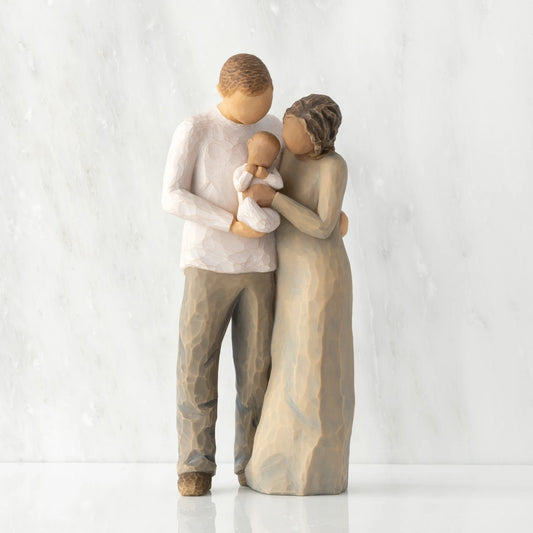 Front view of standing couple, woman has darker skin and hair; man has lighter skin and hair, holding a baby between them.
