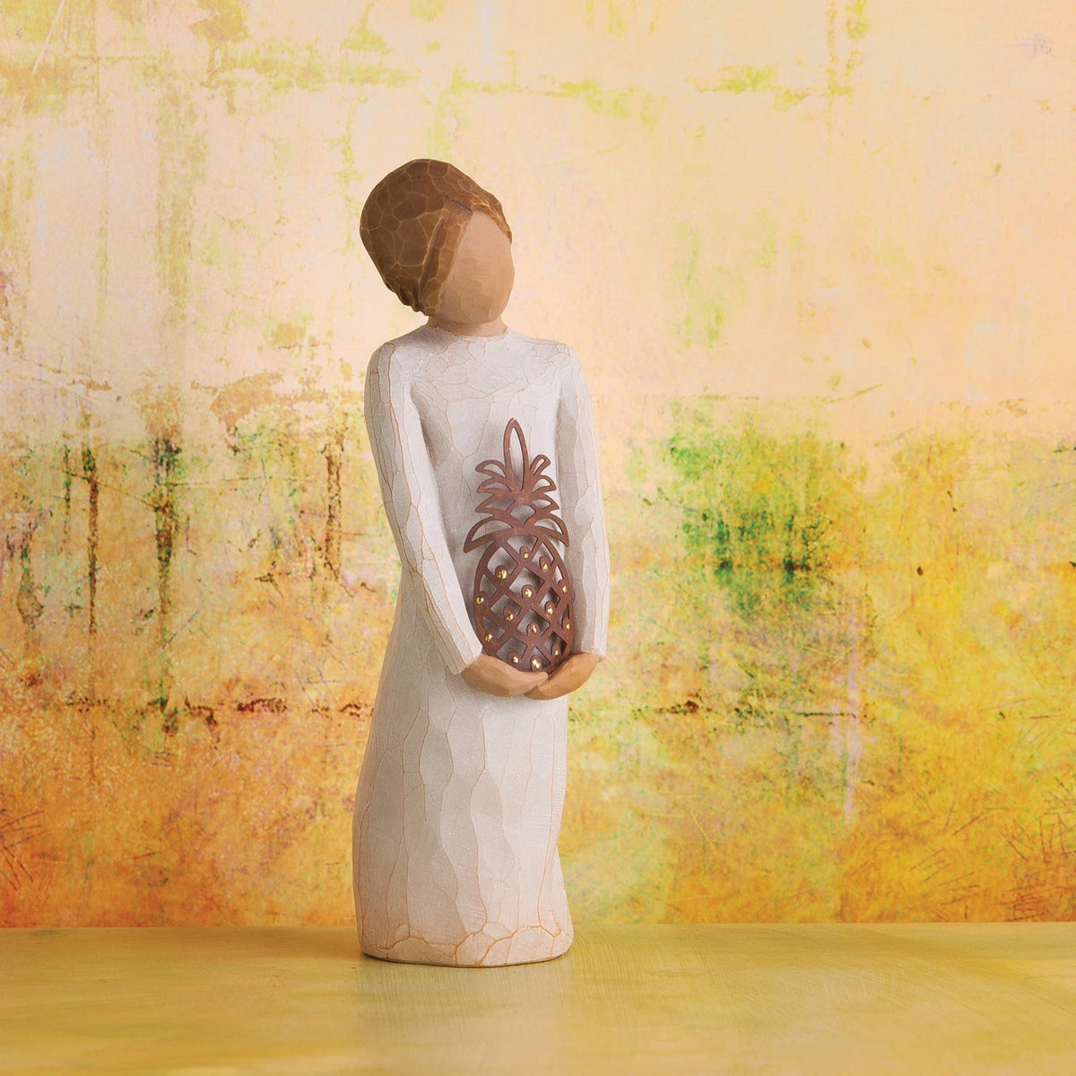 Willow Tree Gracious, 5.5" hand-painted standing resin figure in cream dress, holding pierced-metal pineapple, in front of light orange painting