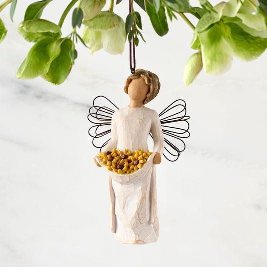 Figure with darker skin, in cream dress with wire wings and wavy brown hair, holding up skirt filled with yellow sunflowers. Hook and loop affixed to figure’s head