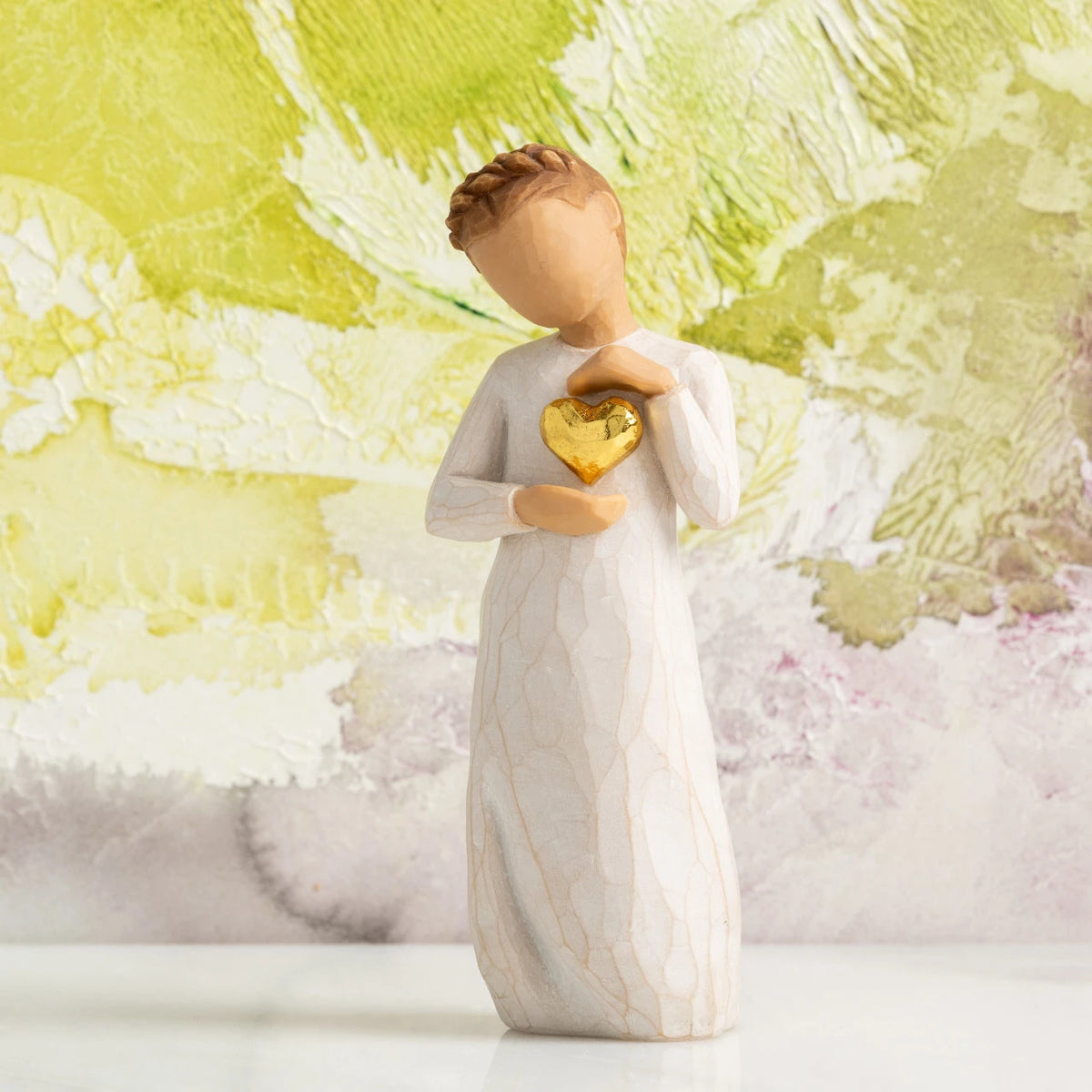Willow Tree Keepsake, 5.5”h hand-painted standing resin figure in cream dress, holding gold-leaf heart against chest, in front of light green painting