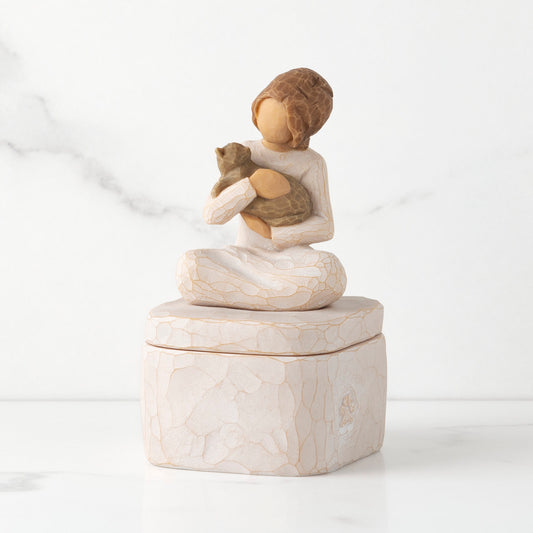Front: cream square resin box with lid, 3-D figure of seated girl holding cat atop lid