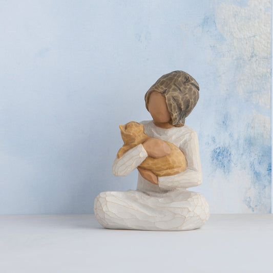 Willow Tree Kindness (girl), 3" hand-painted resin figure in cream dress, darker skin and hair, sitting and holding yellow cat, in front of pale blue painting