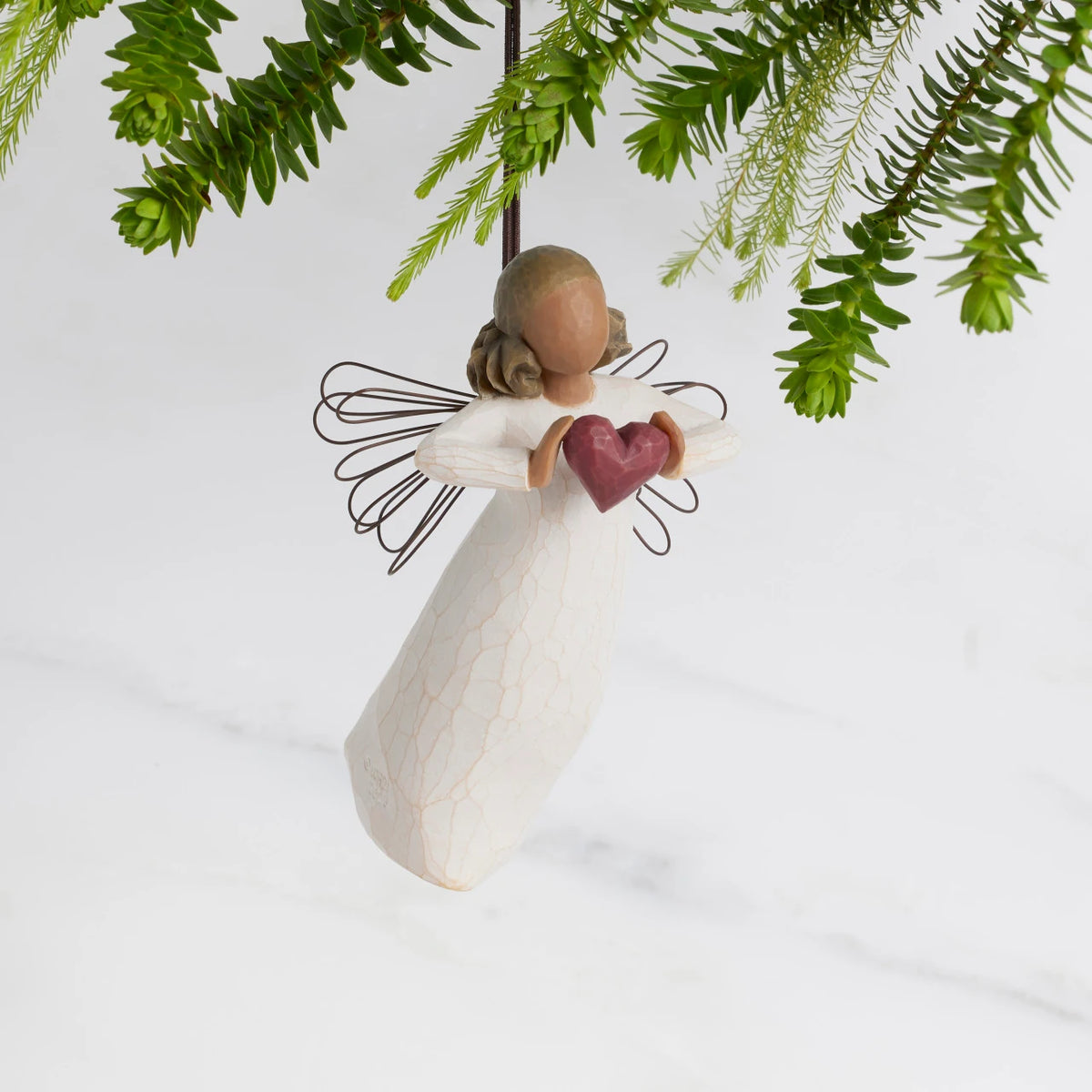 Front view: Darker-skin Angel with wire wings holding red heart. Hook and loop