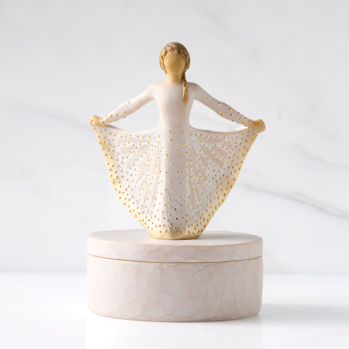 Front view: oval resin box, with 3-D figure in cream and gold carved dress atop lid