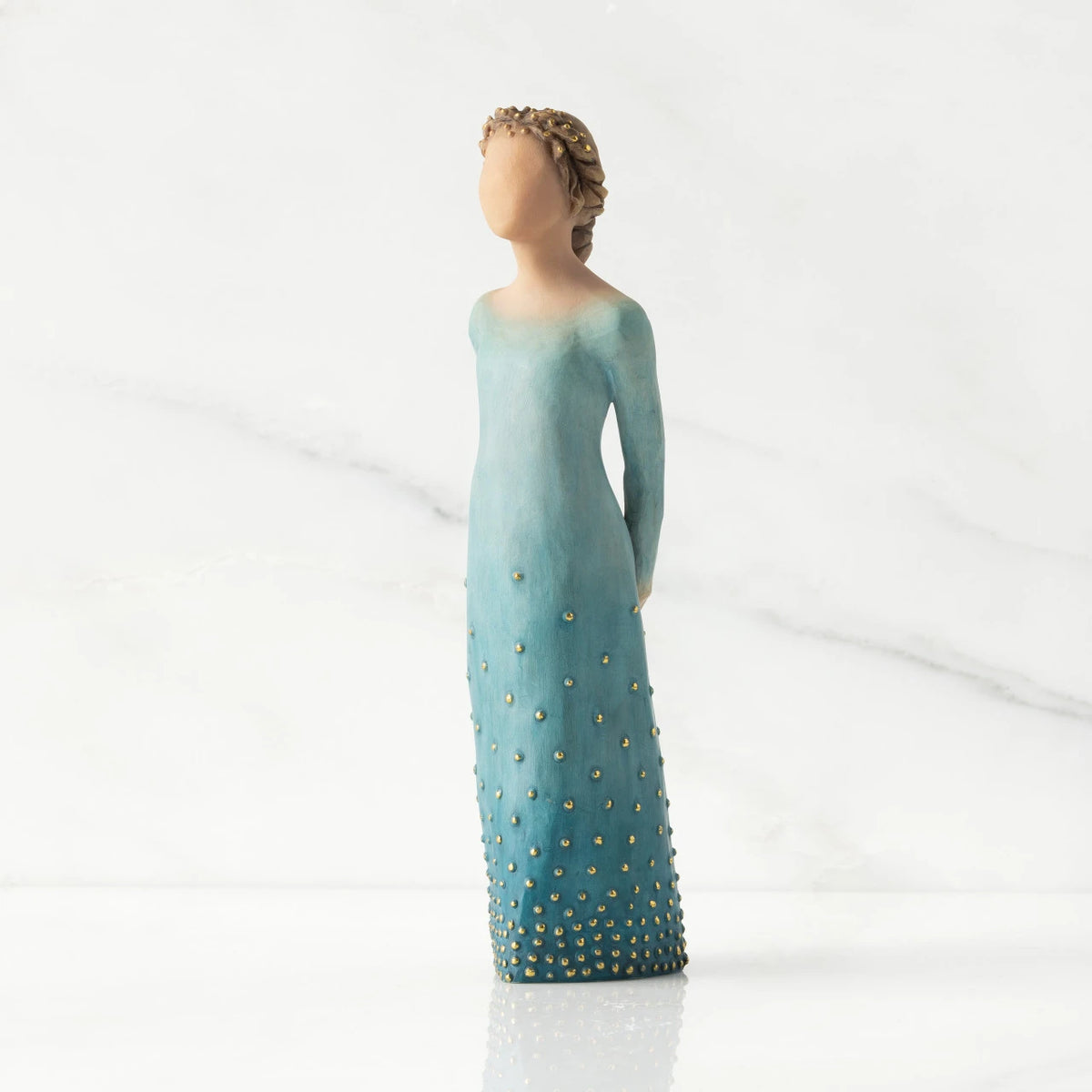 Front/left view: Lighter-skin figure, arms clasped behind back, hair and deep blue ombré garment dotted with gold leaf