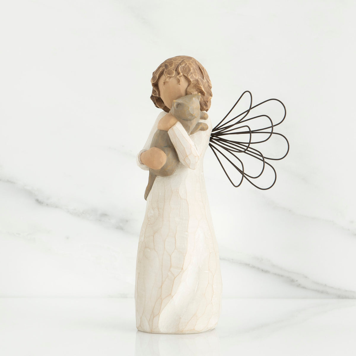 Small brunette angel figurine in white dress holding golden cat
