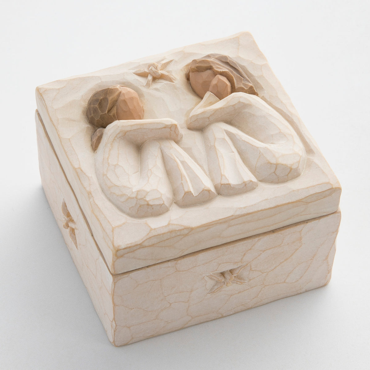 Close view of cream box with carved in image of two brunette girl figurines sitting down