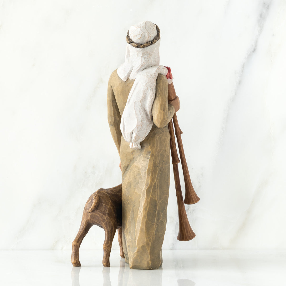 Back view of man figurine in tan dress with white turban - next to donkey figurine