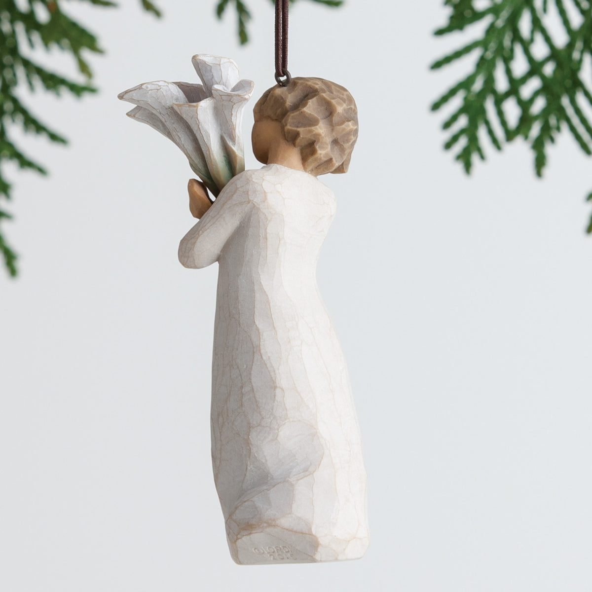 Brunette girl figurine ornament in white dress holding white flowers hanging from green tree branch