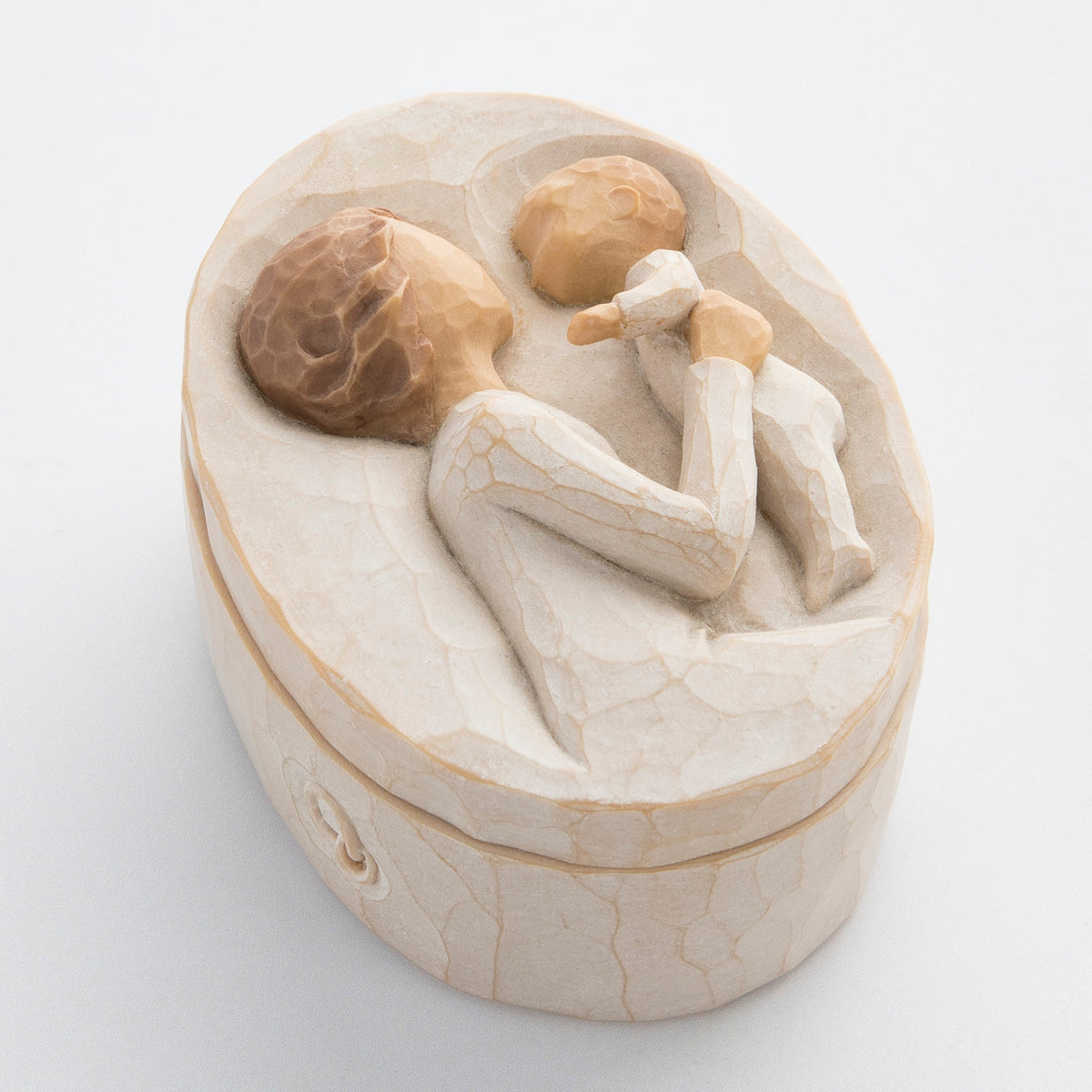 Small cream box with carved in image of brunette girl figurine holding up baby
