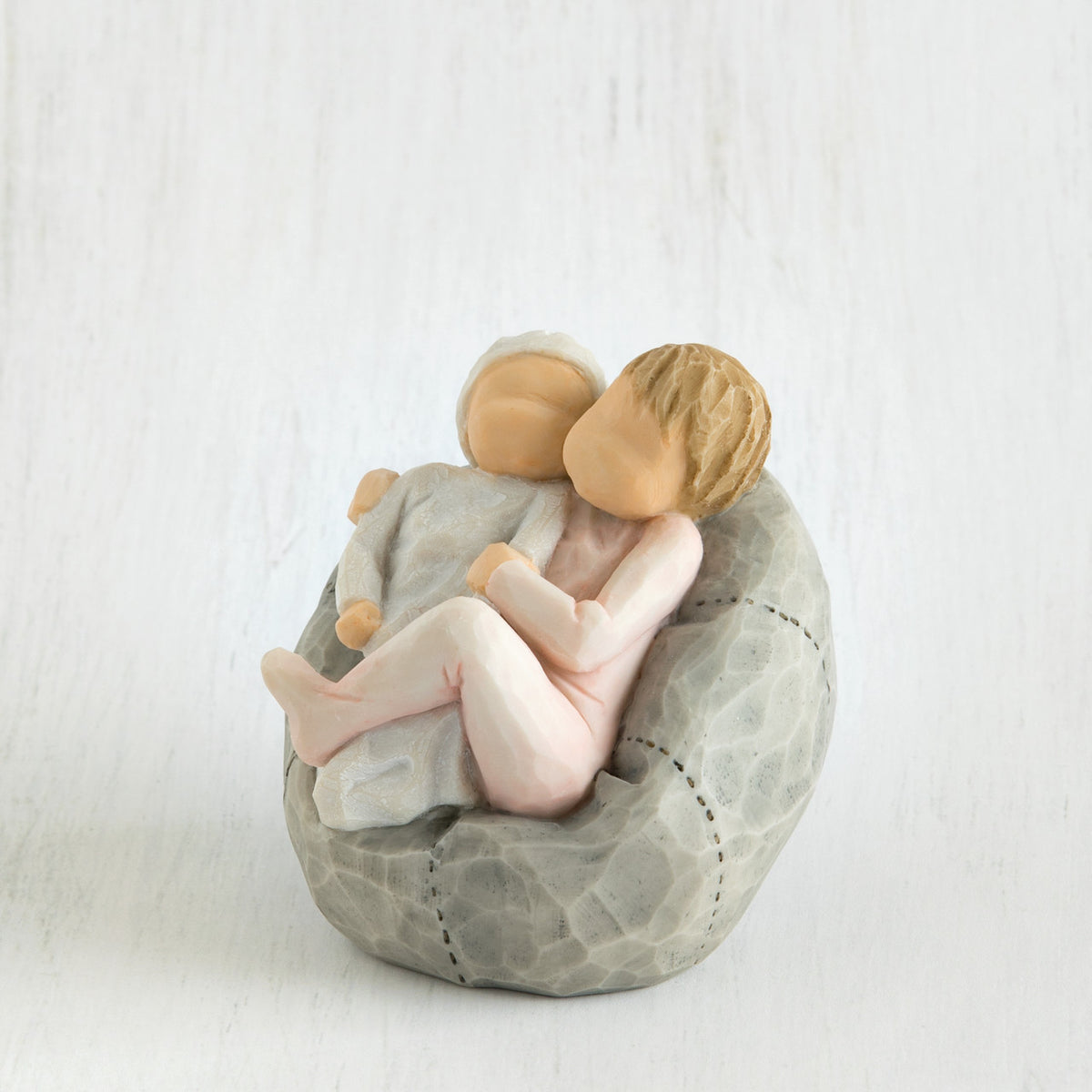 Close view of baby being held by sibling on grey bean bag