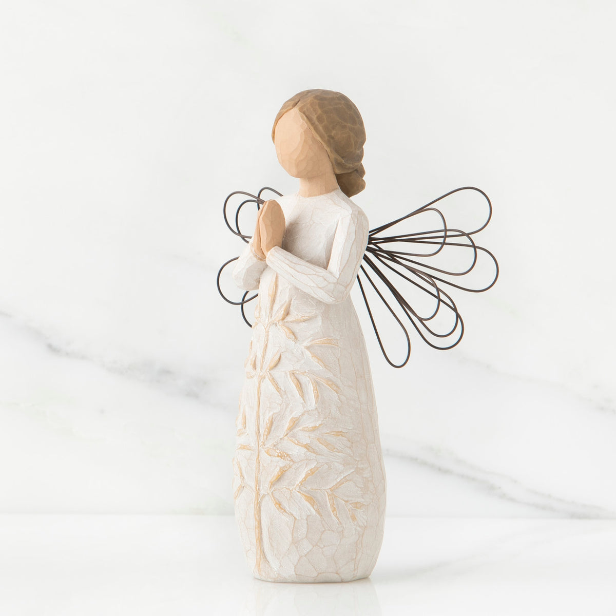 Side view of brunette angel figurine in white dress holding hands in prayer with black wire wings