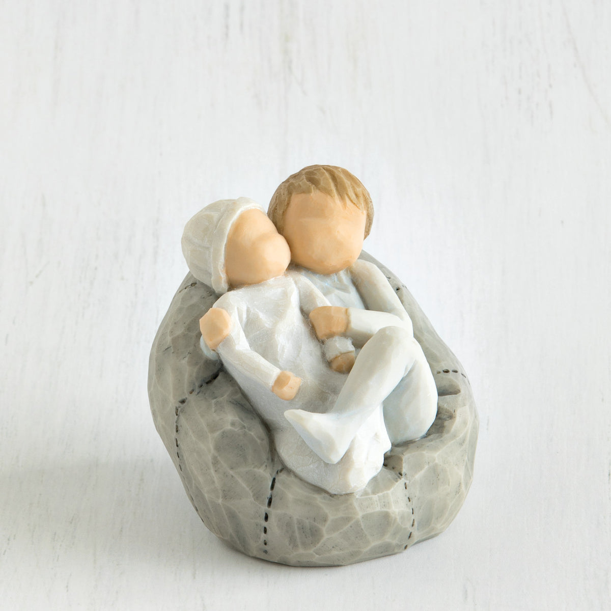 Close view of baby being held by a larger sibling on grey bean bag