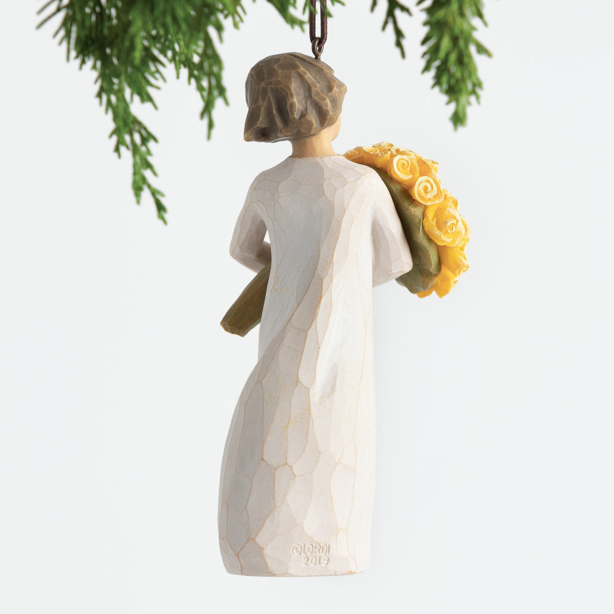 Back view, female figurine in cream dress, holding large bouquet of yellow roses. Hook and loop affixed to figure's head