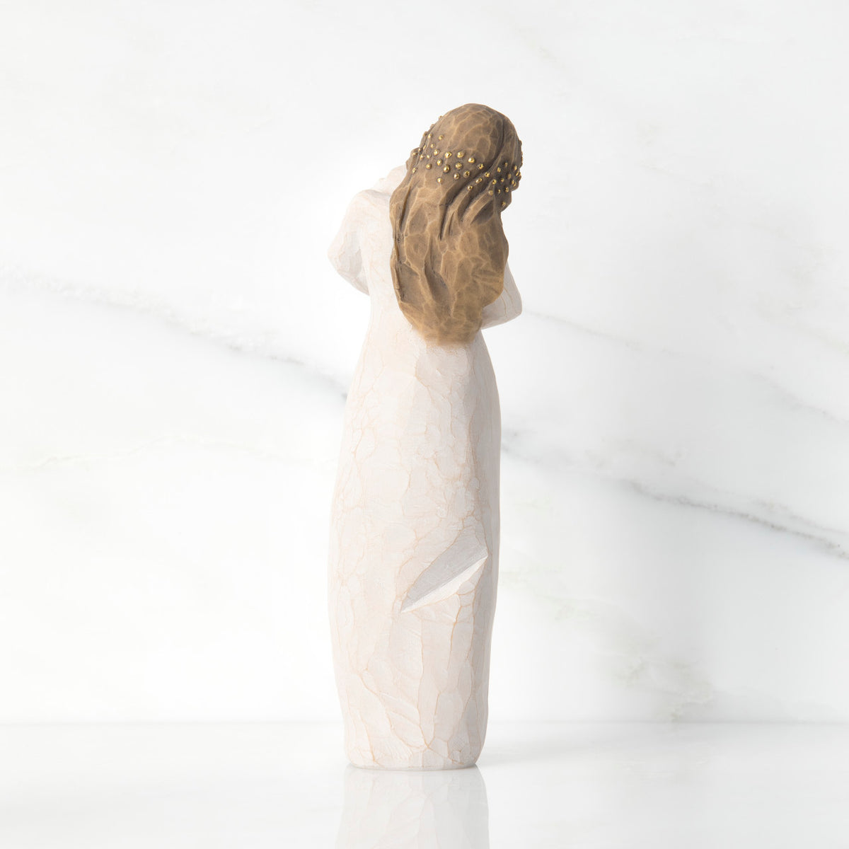 Back view of brunette girl figurine in white dress and has gold dots in her hair