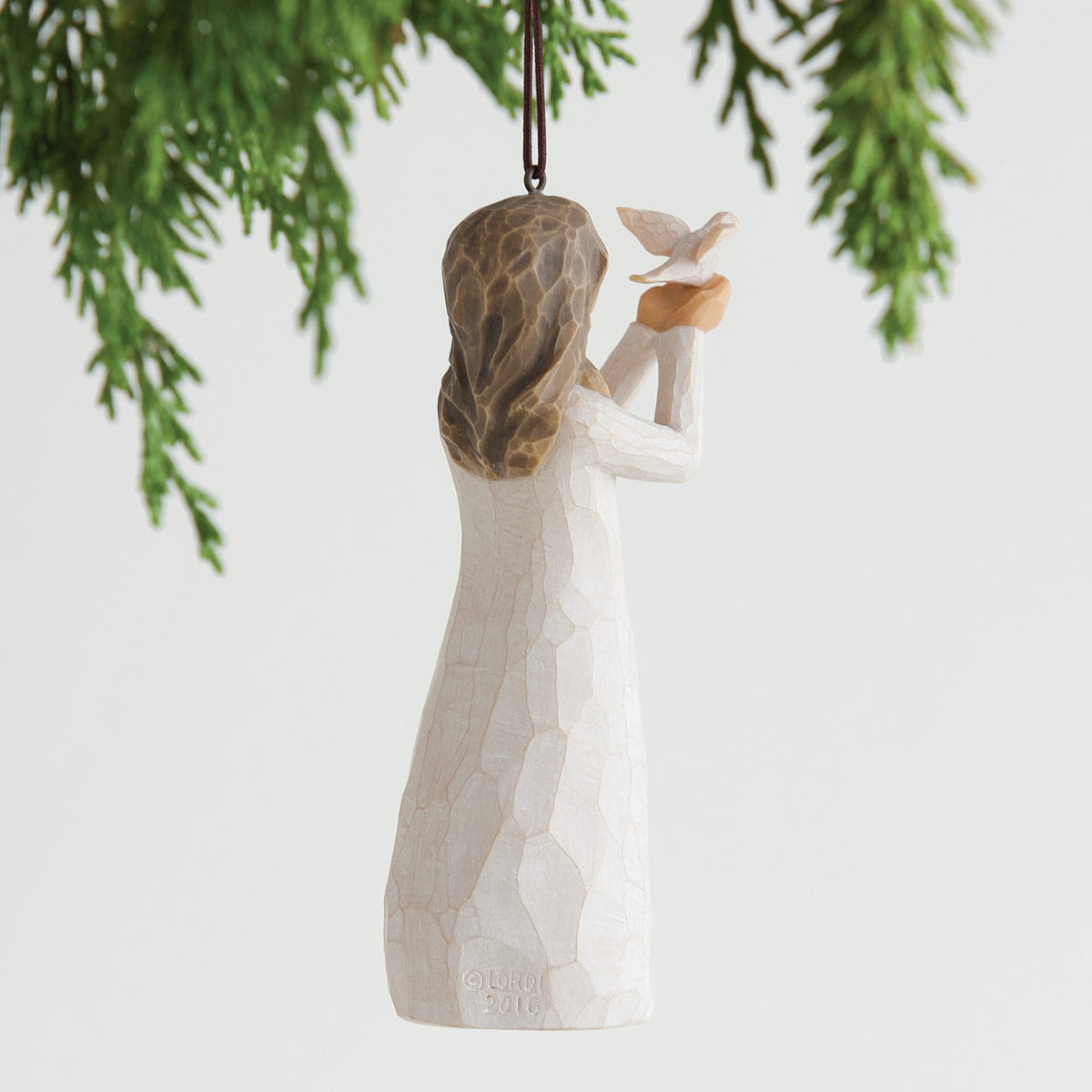 Brunette girl figurine ornament in white dress holding white bird up hanging from tree