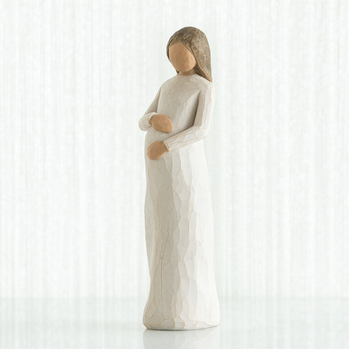 Brunette woman figurine in white holding her stomach facing forward