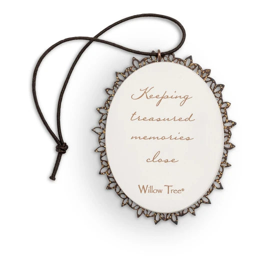 Back of small oval ornament with sentiment written in script on cream, edged in pierced-metal filigree