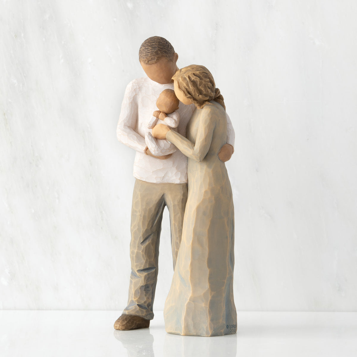 Left view of standing couple, woman has lighter skin and hair; man has darker skin and hair, holding a baby between them.