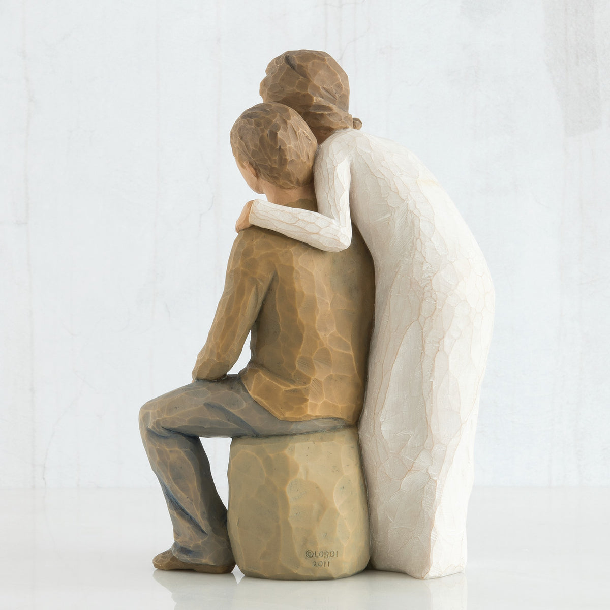 Back view - woman figurine in white dress hugging man figurine in brown shirt and blue jeans