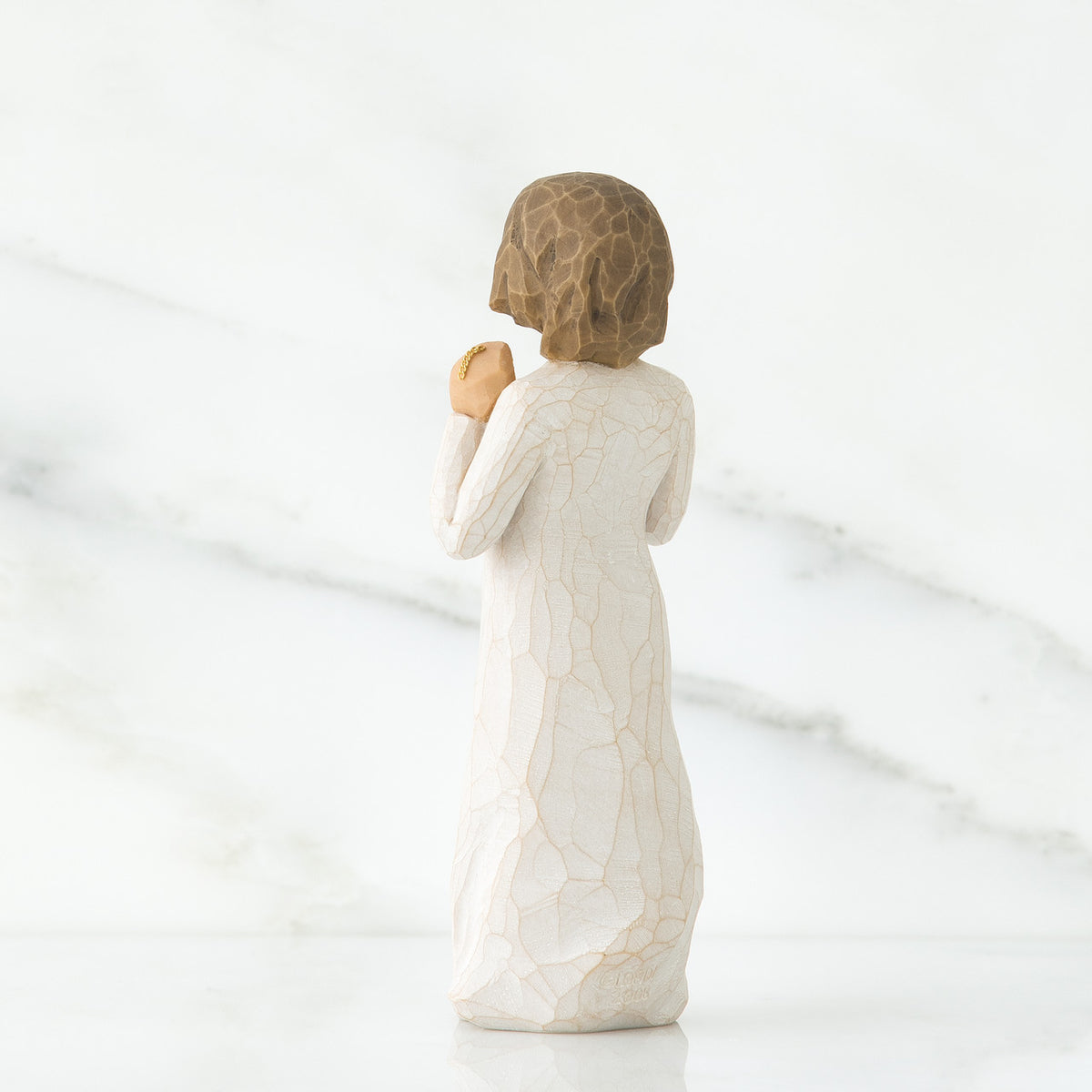 Back view of brunette girl figurine in white dress