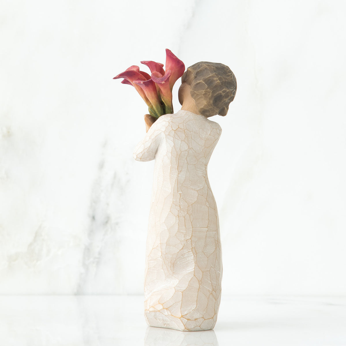 Back view of little girl with short brown hair holding a cluster of red calla lilies