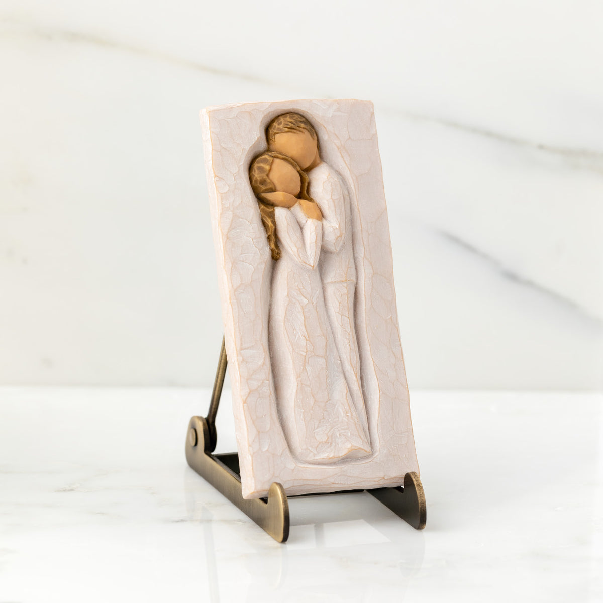 Willow Tree Embrace Plaque, 5.75”h x 2.68”w x .5”d hand-painted resin bas-relief carving of embracing couple. Plaque displayed on Plaque Stand on marble