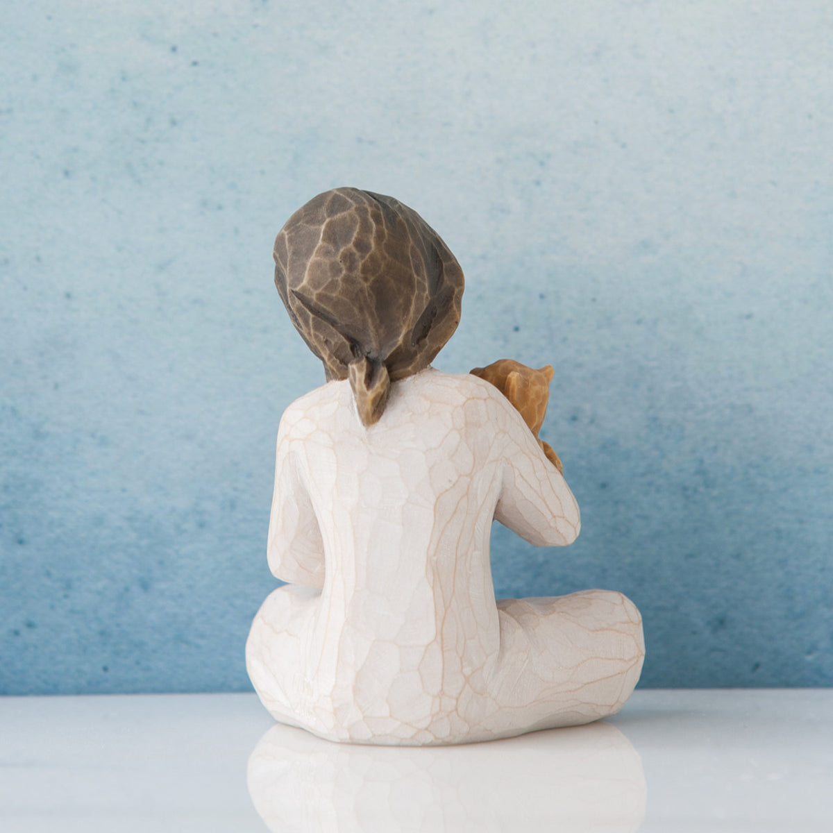 Small brunette girl in white facing away from the front towards the blue wall