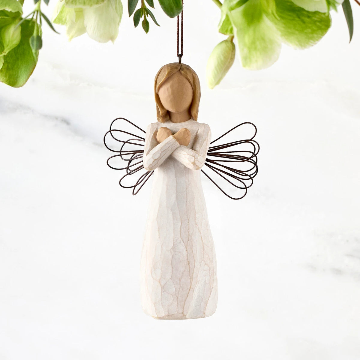 Figure in cream dress with wire wings and arms crossed in front of chest, ornament loop fixed to figure's head