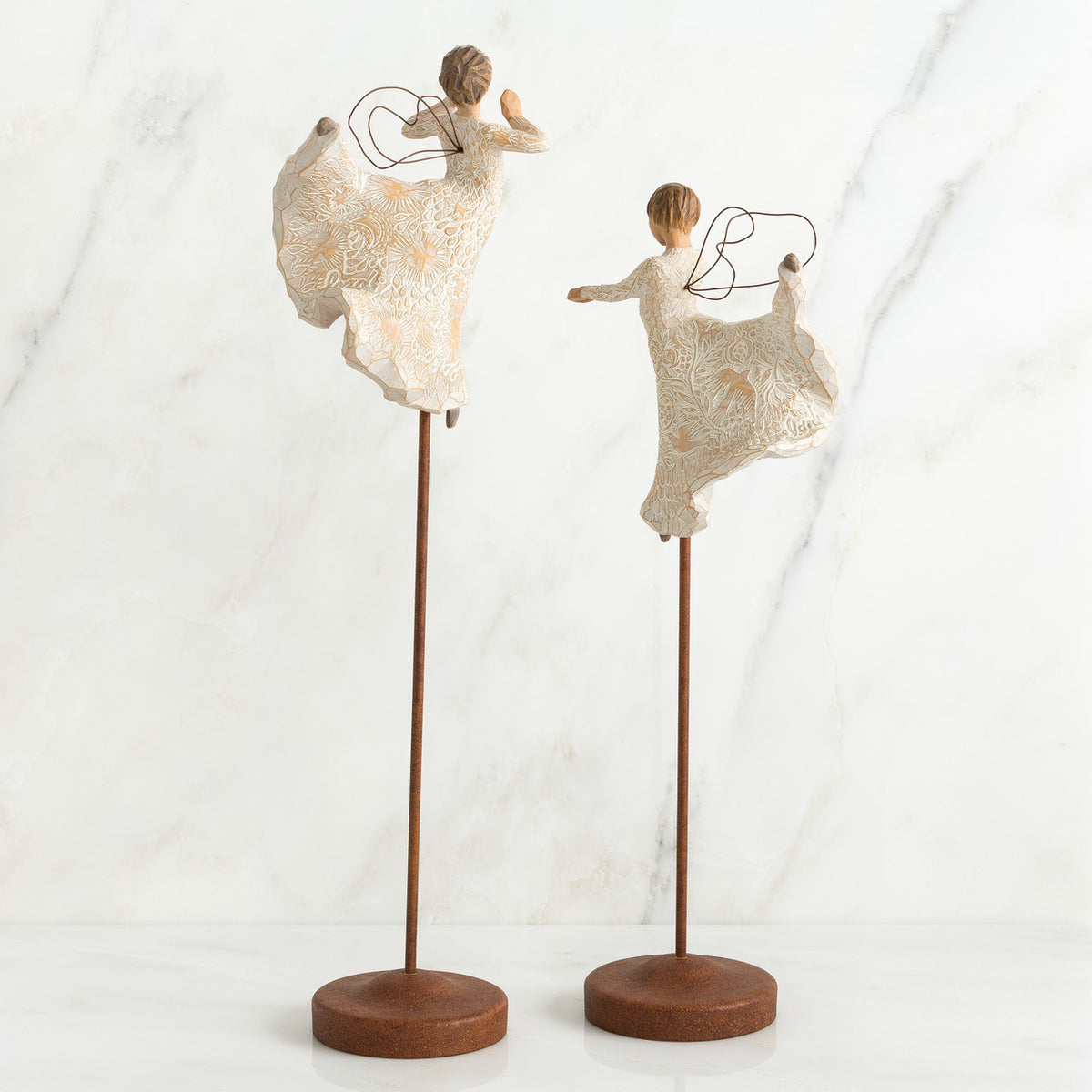 Two angel figurines in white dresses on wooden stands