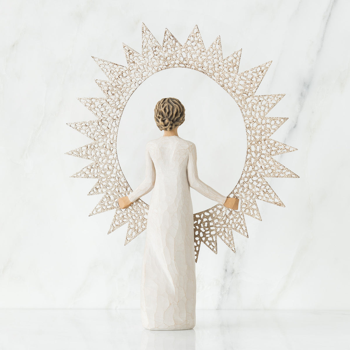 Back view of brunette girl figurine in white dress holding sun figurine up