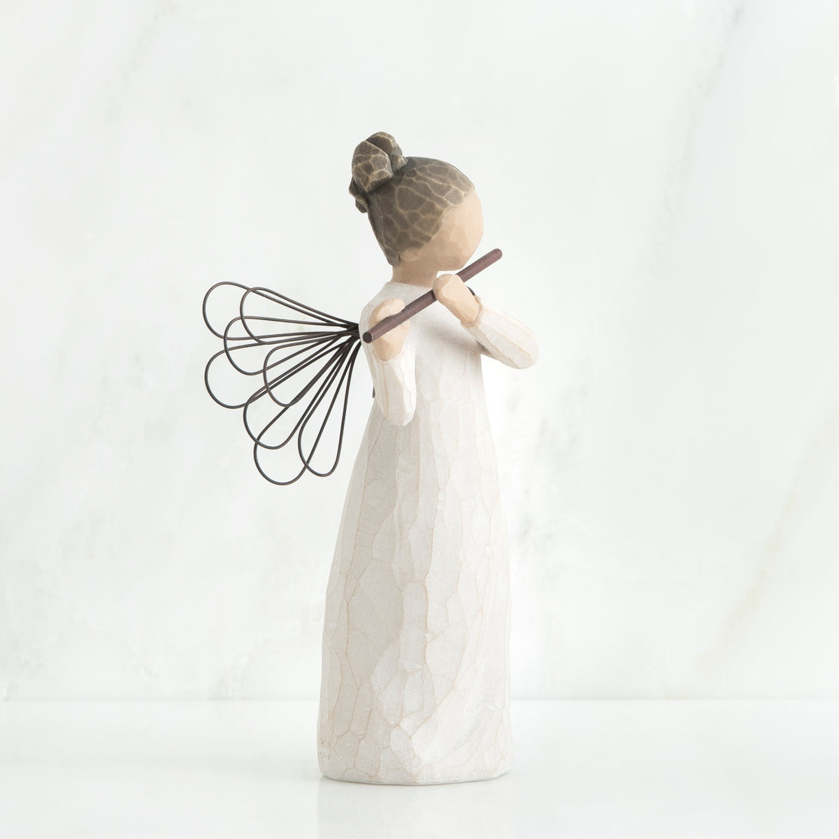 Side view of brunette girl angel figurine in white dress playing flute