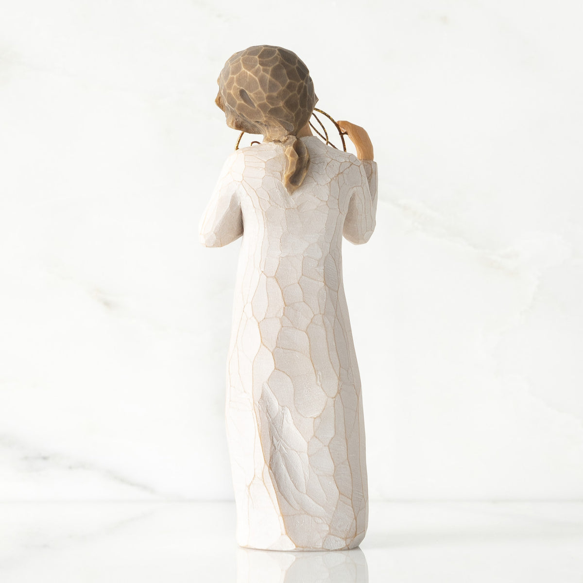 Back view, standing female figure in cream dress, holding gold wire circle in which is written 'love you'