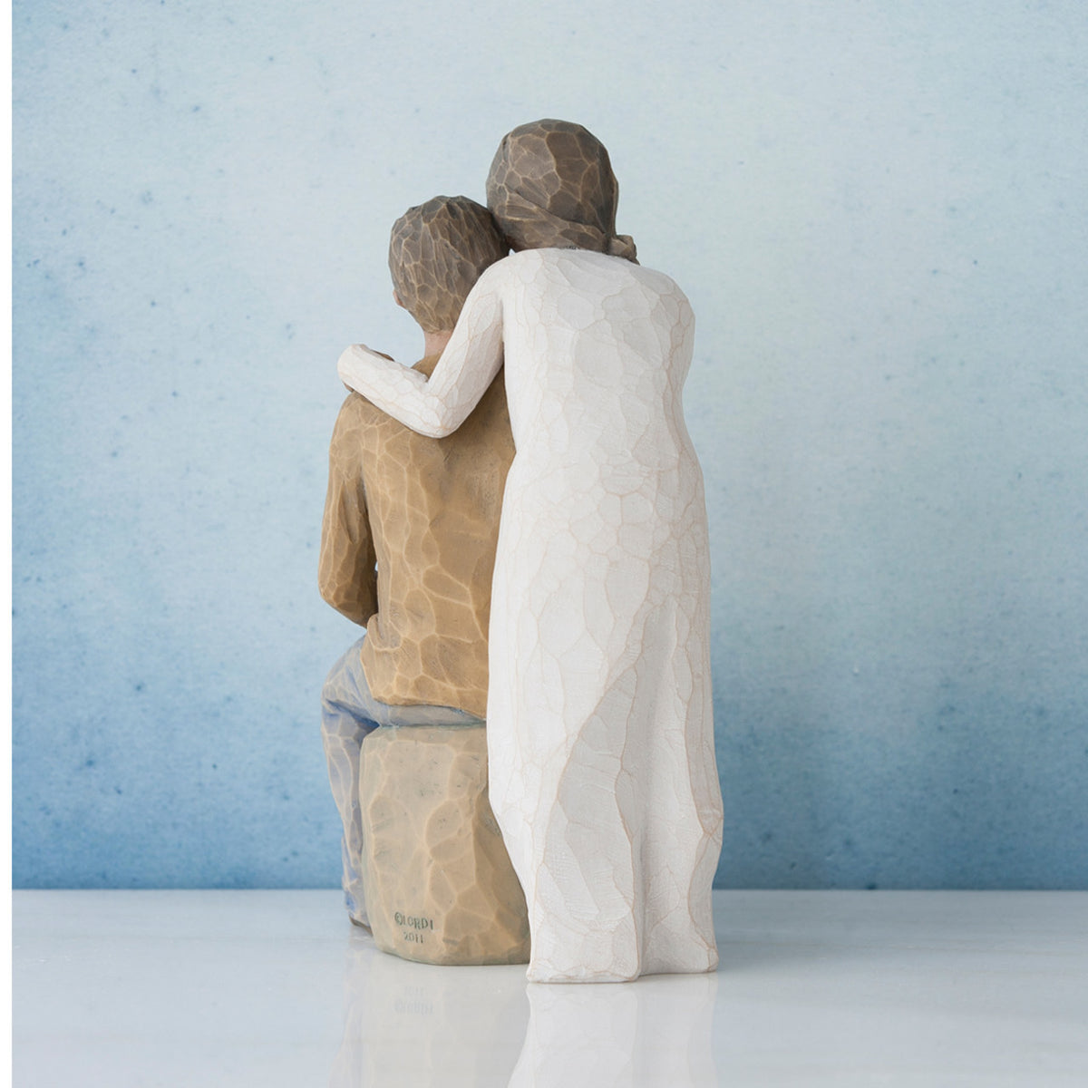Woman figurine in white dress standing over man sitting down - all facing away from front