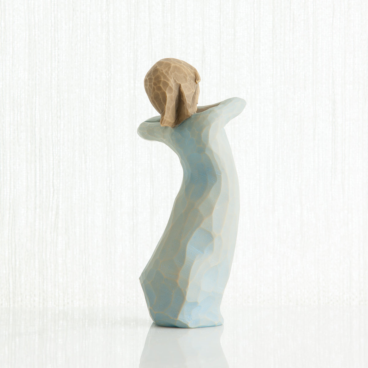 Back view of girl figurine in blue dress standing with her arms up