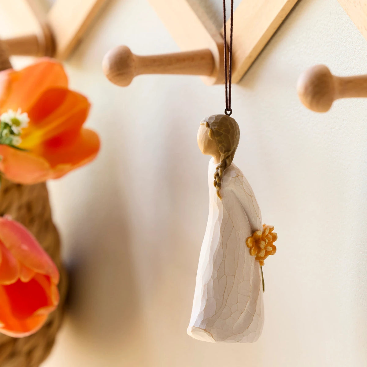Willow Tree For You Ornament, 4.25”h hand-painted resin figure in cream dress, holding bouquet of orange flowers behind back, brown elastic cord, hanging on wooden peg