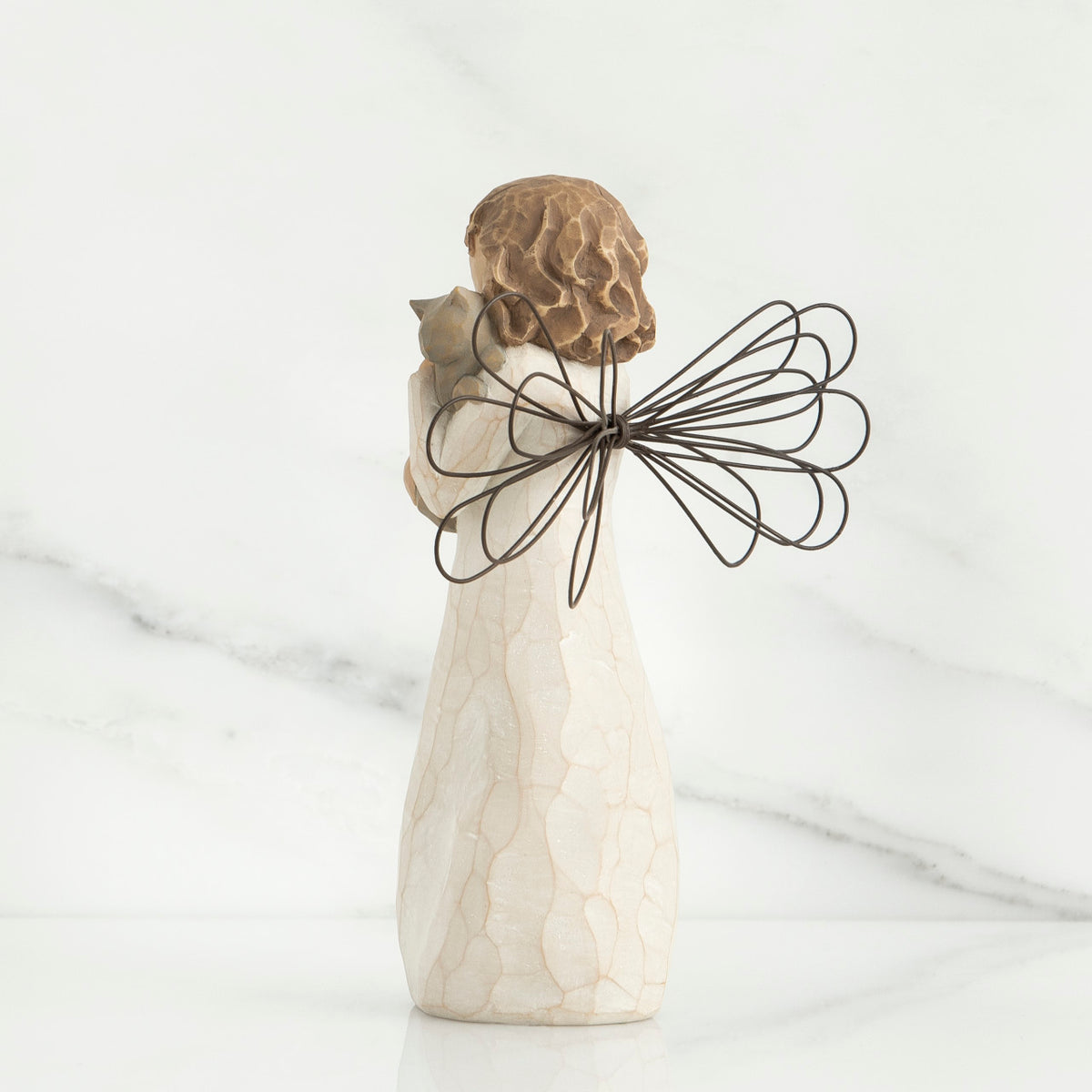 Back view of brunette angel figurine in white dress holding grey cat