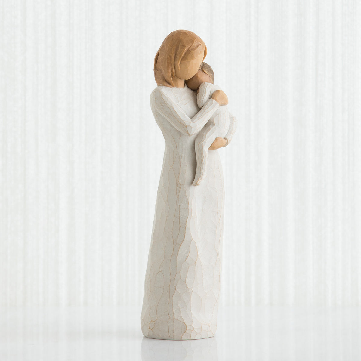 Front view of blonde woman figurine in white dress holding baby