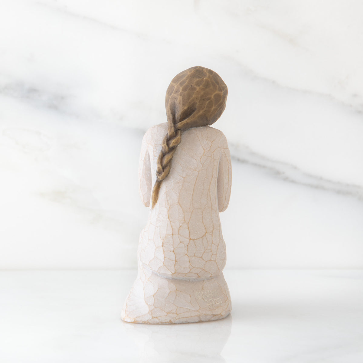 Back view of kneeling female figure in cream dress, with wire butterfly on extended hands
