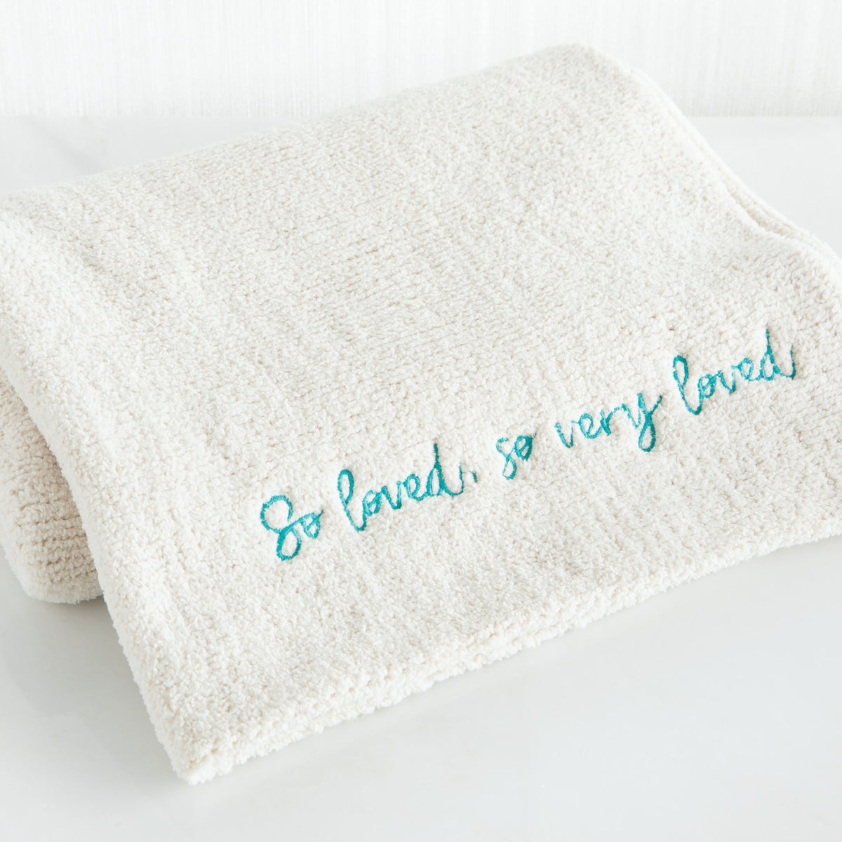 Close view of white towel with 'so loved, so very loved' in light blue