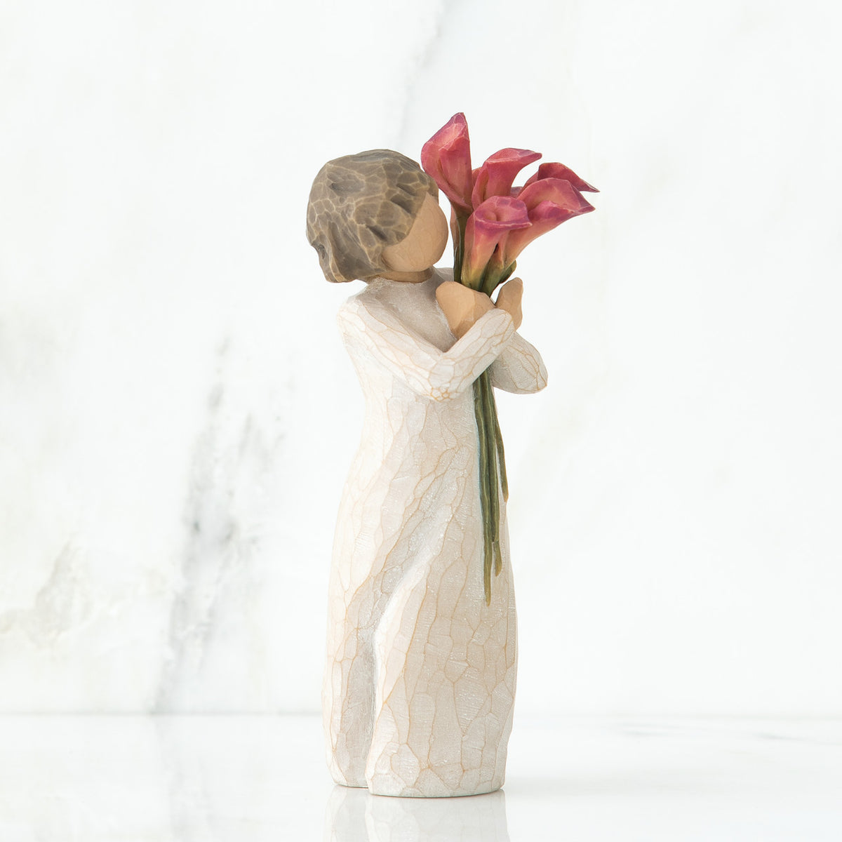 Left side view of little girl with short brown hair holding a cluster of red calla lilies