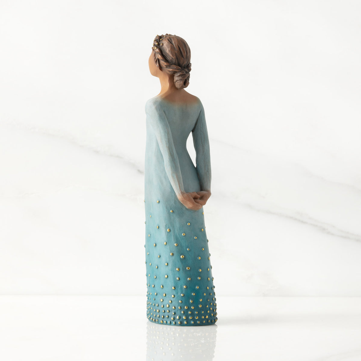 Facing left/back: Darker-skin figure, arms clasped behind back, hair and deep blue ombré garment dotted with gold leaf