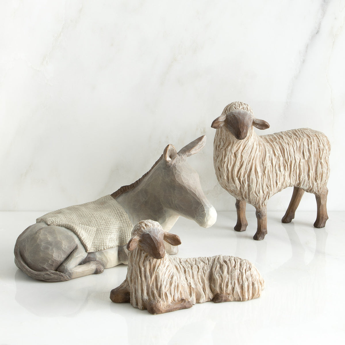 Two white sheep figurines in between white donkey figurine laid out