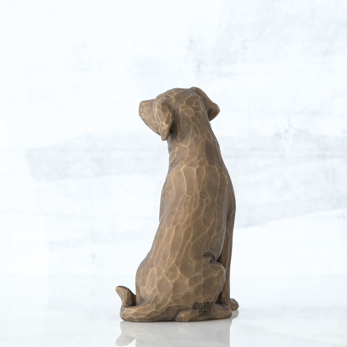 Dark brown dog figurine sitting - back view